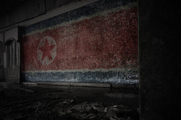 painted flag of north korea on the dirty old wall in an abandoned ruined house.