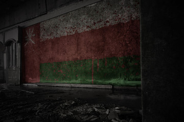 Fototapeta na wymiar painted flag of oman on the dirty old wall in an abandoned ruined house.