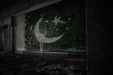 painted flag of pakistan on the dirty old wall in an abandoned ruined house.