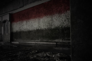 painted flag of yemen on the dirty old wall in an abandoned ruined house.