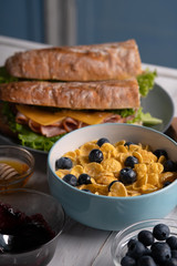 Homemade food. Delicious fresh breakfast. Morning meal. Lunch. Baguette, corn flakes, sandwich. Kitchen. White table
