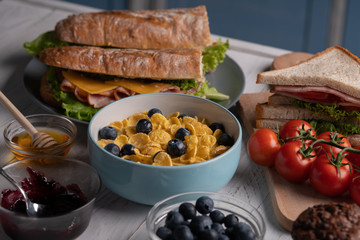 Traditional food. Delicious breakfast. Homemade meal. Baguette, sandwich, muffin, sweet corn flakes. Kitchen. White table.
