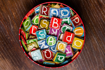 Tin can full of colorful ceramic tiles with letters