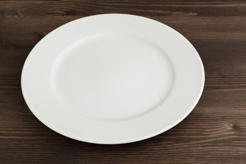 White round china plate on a wooden brown table.