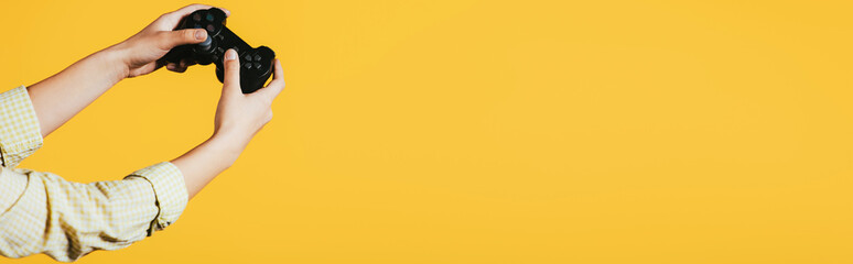 KYIV, UKRAINE - APRIL 16, 2019: cropped view of girl holding joystick, isolated on yellow © LIGHTFIELD STUDIOS