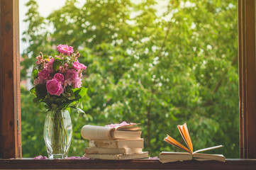 Book, croissant, cup of tea and roses on a wooden window. Read books. Romantic concept. Vintage style 