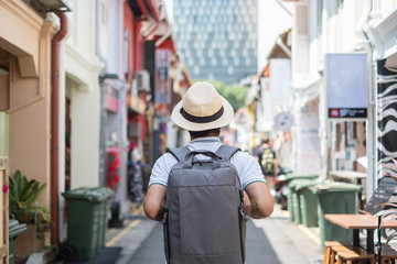 Young man hipster traveling with backpack and hat, happy Asian traveler walking at Haji Lane and...