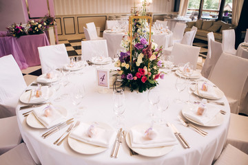 Round white table with elegant compositions from natural flowers. Banquet at the luxury wedding. Elegant design wedding table.