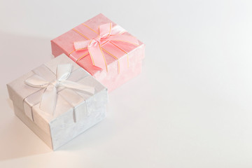 Festive background with gift wrap with two boxes of pink and silver color with a bow in pastel colors on a white background with a copy space