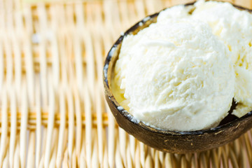 Artisan vegan non-diary coconut ice cream in shell bowl on wicker table. Healthy sweets desserts summer vacation concept. Cafe menu template with copy space