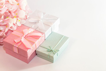 Festive background with gift wrapping with pink, silver, pale green boxes with bow and artificial hydrangea flowers in pastel colors on a white background with copy space