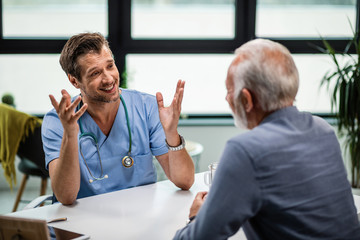 Happy mid adult doctor talking to senior patient at his office.