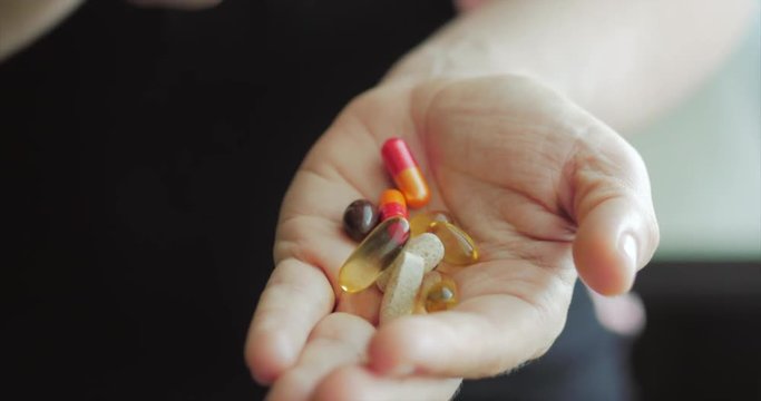 Close-up of Female Hands, Someone Pours a Bunch of Prescription Opiate Pills into the Hand. Concept of Health, Drugs, Contraception.