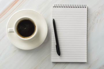 Open notebook with cup of coffee on marble desk. Workplace, work table. Top view.