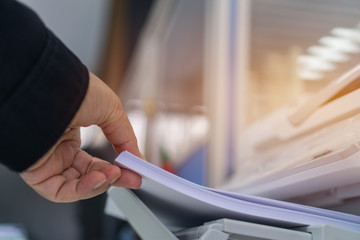 Business printer / printing documents in office concept: Businessman press white paper in laser...