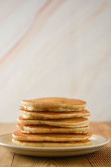 Stack of pancakes on wooden background. Homemade american pancakes, isolated.