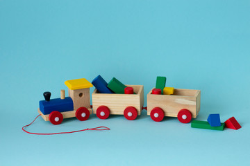 Wooden colorful toy train with details on a blue background. Early childhood education, learning to count, preschool and kids game concept