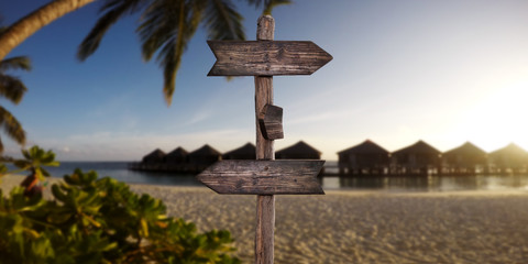 Wooden Arrow Sign at Sandy Beach at Tropical Island. Summer Vacation Concept