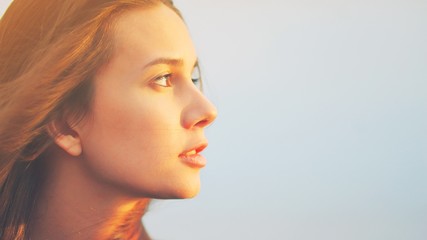 Beautiful young woman relaxing and enjoying sun at sunset. Beauty sunshine girl side profile...