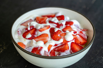 Red strawberry and white yogurt brulee. Fruit dessert on breakfast with wedges of perfectly ripe in season strawberry, closeup
