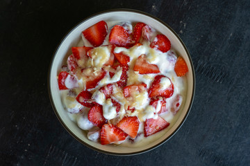 Red strawberry and white yogurt brulee. Fruit dessert on breakfast with wedges of perfectly ripe in season strawberry, closeup