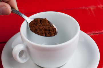 White coffee cup with metal spoon isolated on a red background.