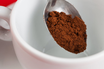 White coffee cup with metal spoon isolated on a red background.
