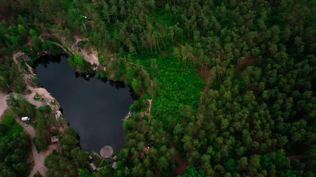 4K Arial Drone shot. Birds eye view of a lake surrounded by a lush green forest.