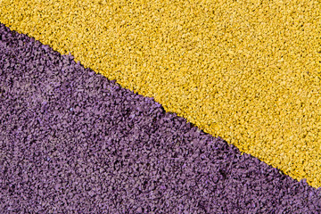 Protective yellow-purple rubber crumb coating. The texture is a safe rubberized surface for playgrounds and sports fields. Close up