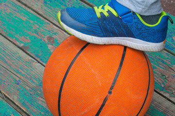 baby foot in blue sneaker on orange basketball ball