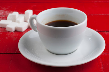 White coffee cup with sugar cubes isolated on a red background