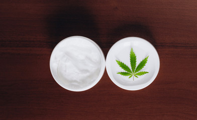 Moisturizing hemp hand cream in dose with green cannabis leaf. Cannabis cosmetics. Cream from biological and ecological plants of hemp vegetable pharmaceutical oil CBD
