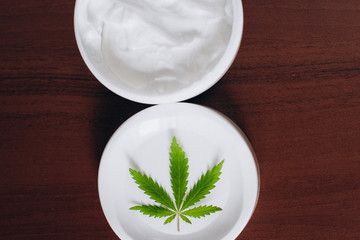 Moisturizing hemp hand cream in dose with green cannabis leaf. Cannabis cosmetics. Cream from biological and ecological plants of hemp vegetable pharmaceutical oil CBD