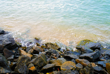 Southern tropical summer ocean coast with rocks and rocks. Lagoon with a yellow sandy beach and azure water.