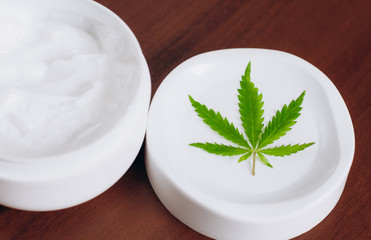 Moisturizing hemp hand cream in dose with green cannabis leaf. Cannabis cosmetics. Cream from biological and ecological plants of hemp vegetable pharmaceutical oil CBD