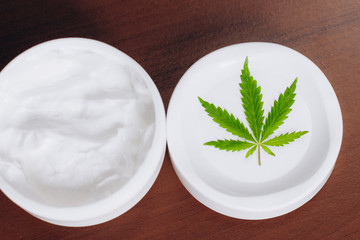 Moisturizing hemp hand cream in dose with green cannabis leaf. Cannabis cosmetics. Cream from biological and ecological plants of hemp vegetable pharmaceutical oil CBD