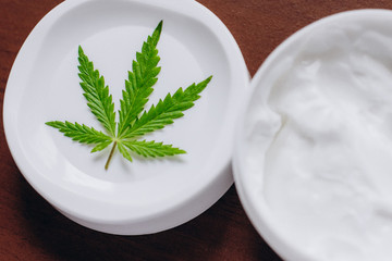 Moisturizing hemp hand cream in dose with green cannabis leaf. Cannabis cosmetics. Cream from biological and ecological plants of hemp vegetable pharmaceutical oil CBD