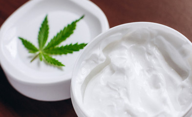 Moisturizing hemp hand cream in dose with green cannabis leaf. Cannabis cosmetics. Cream from biological and ecological plants of hemp vegetable pharmaceutical oil CBD