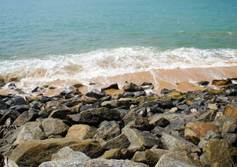 Southern tropical summer ocean coast with rocks and rocks. Lagoon with a yellow sandy beach and azure water.