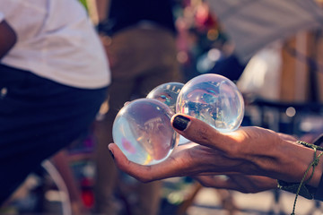 Sorcerer's hands holding juggling crystal balls at public summer festival