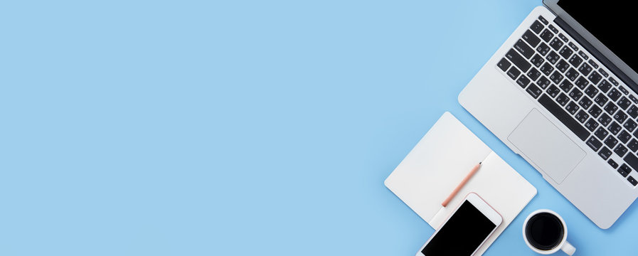 Girl write on open white book or accounting on a minimal clean light blue desk with laptop and accessories, copy space, flat lay, top view, mock up