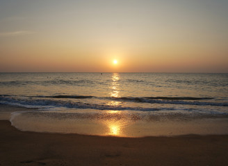 Southern tropical summer ocean coast at sunset. Lagoon with waves in which the sun is reflected.