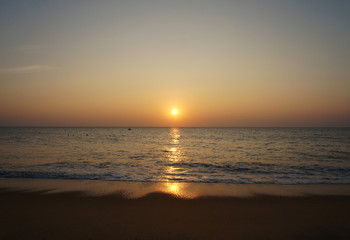 Southern tropical summer ocean coast at sunset. Lagoon with waves in which the sun is reflected.