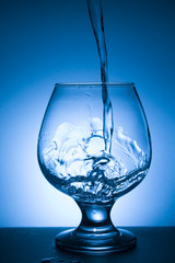 glass of water with splash on blue background