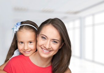 Young woman with little girl and beautiful flowers at room
