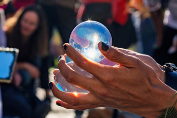 Sorcerer's hands holding juggling crystal balls at public summer festival