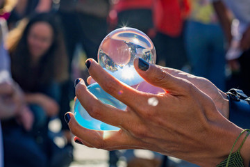 Sorcerer's hands holding juggling crystal balls at public summer festival