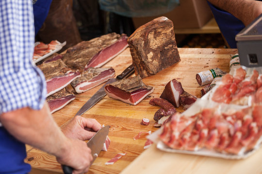 VAL DI FUNES, ITALY - OCTOBER 01, 2016: Traditional smoked speck sliced on site during the "Speckfest" celebration in Val di Funes, Dolomites.