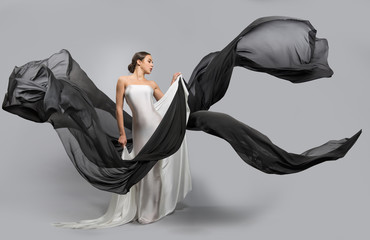 fashion portrait of a beautiful woman in a white and black dress. The fabric flies in the wind.