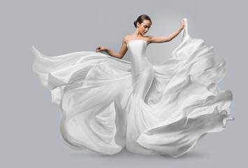 Fashion portrait of a beautiful woman in a waving white dress. Light fabric flies in the wind. - Powered by Adobe